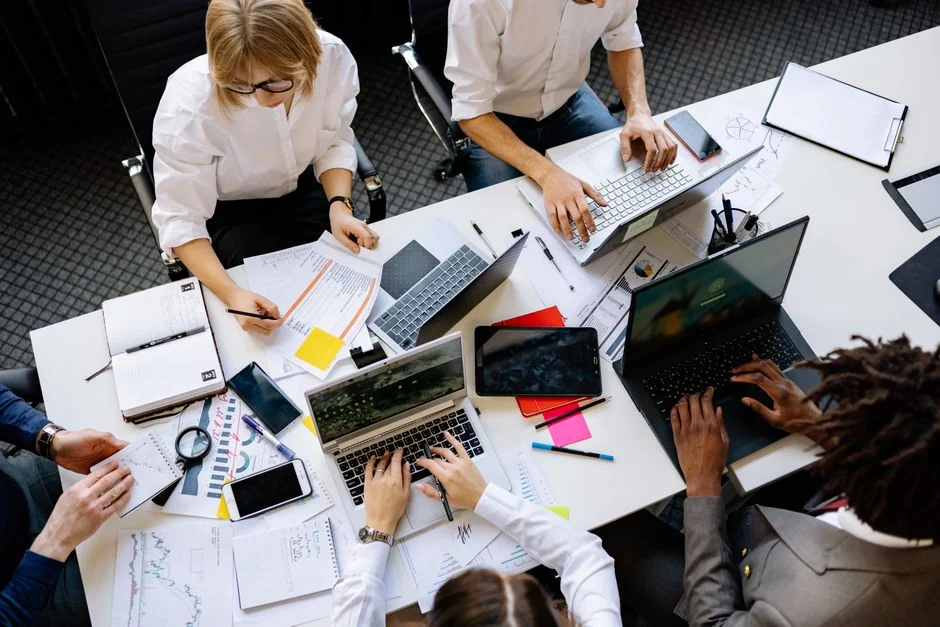 A diverse team collaborating on digital marketing strategies at a desk, using laptops and tablets.
